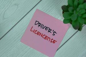 Concept of Driver's License write on sticky notes isolated on Wooden Table. photo