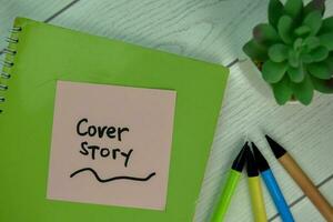 Cover Story write on sticky notes isolated on Wooden Table. photo