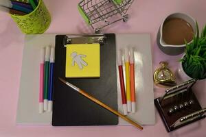 Top view of the cutting paper illustration a man on a pink table, preparing to do homework in a clipboard. Drawing Working Desk Concept photo