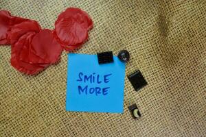 Smile More write on sticky notes isolated on Wooden Table. photo