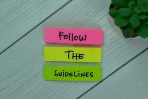 Concept of Follow the Guidelines write on sticky notes isolated on Wooden Table. photo