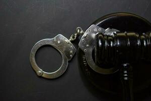 handcuffs and black gavel isolated on black background. Justice and law concept photo