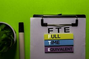 FTE. Full Time Equivalent acronym on sticky notes. Office desk background photo