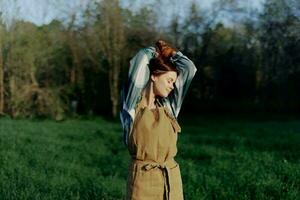 Portrait of a woman with a beautiful smile in her work clothes and apron in nature, enjoying relaxation after work in the sunset sunlight photo