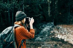 mujer con un cámara en naturaleza en el montañas cerca el río lado ver foto