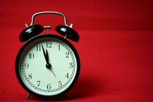 Clock ticking to 12 o'clock on the red background photo