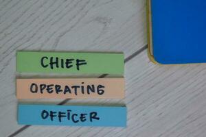 Chief Operating Officer write on sticky notes isolated on Wooden Table. photo