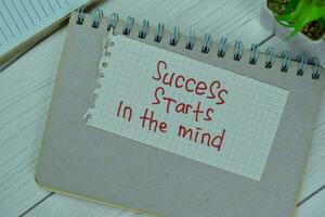 Concept of Success Starts in the Mind write on sticky notes isolated on Wooden Table. photo