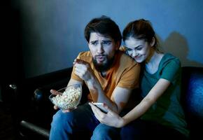 Emotional woman and man on the couch with popcorn watching TV photo