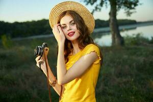 bonito mujer rojo labios encanto sombrero en su cabeza un cámara en el manos de un pasatiempo foto