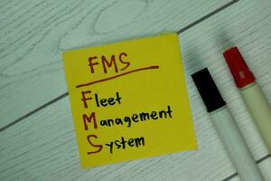 FMS - Fleet Management System write on sticky notes isolated on Wooden Table. photo