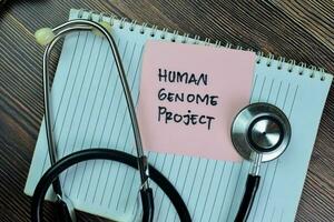 Concept of Human Genome Project write on sticky notes isolated on Wooden Table. photo