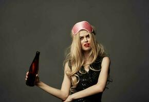 Beautiful blonde with a bottle of beer in her hand and a pink mask on her head photo