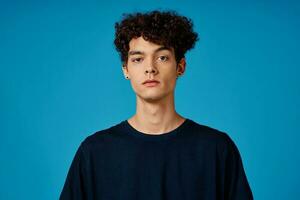 guy in black t-shirt with curly hair blue background photo