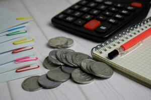 Calculator and the stack of coint isolated on office desk. calculating salary or tax concept photo