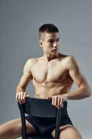 sexy guy with muscular muscles sitting on a chair cropped view photo