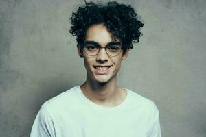 funny curly guy in a white t-shirt glasses emotions studio fashion photo