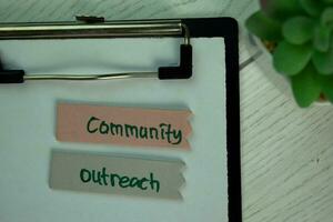 Community Outreach write on sticky notes isolated on Wooden Table. photo