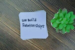 Concept of We Build Relationships write on sticky notes isolated on Wooden Table. photo