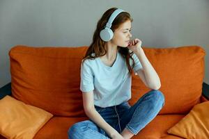 mujer sentado en el sofá a hogar escuchando a música en auriculares apartamentos foto