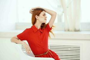 red-haired woman in red dress posing on a chair fashion photo