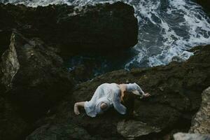 Beautiful bride in a white dress lying on a stone in a white dress landscape photo