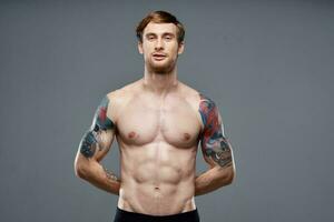sporty man with tattoos on his arms pumped up press macho gray background photo