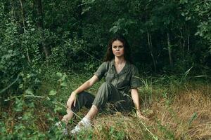 woman in overalls and sneakers rest on the grass the forest photo