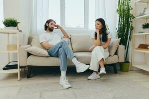 A young married couple sitting on the couch not talking to each other, family quarrels and discontent. Lifestyle in misunderstanding and unwillingness to work on the relationship for love photo