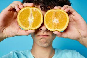 man with curly hair oranges holding fruit studio blue background photo