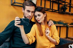 a woman photographs herself and a young man at a table in a cafe restaurant friends couple in love photo