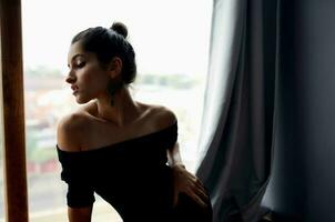 beautiful woman in a black dress near the window posing lifestyle studio photo