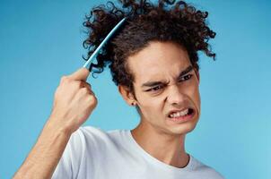 problems with combing hair young guy in t-shirt and combing curls model photo