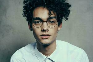 curly-haired man in glasses and in a white shirt on a fabric background smile model close-up portrait photo