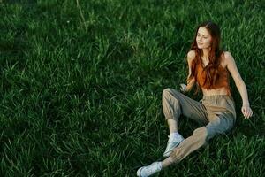 A girl sits on the grass in the park and enjoys the beautiful view of the summer sunset photo