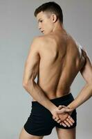 handsome man with pumped up arm muscles naked back gray background photo