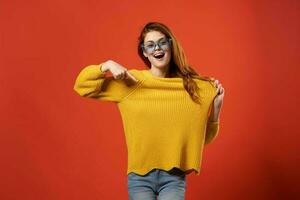 woman in a yellow sweater blue glasses studio fashionable hairstyle red background photo