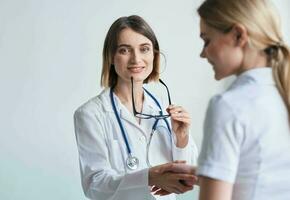 beautiful woman doctor with stethoscope shaking hands with female patient photo