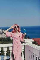 atractivo mujer disfrutando un vistoso cóctel en el panorámico ver hotel terraza Bebiendo alcohol foto