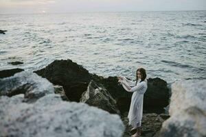 Woman in white dress travel stones ocean landscape unaltered photo