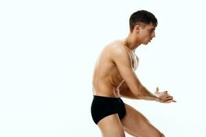 side view of a sexy athlete with a pumped-up torso and in black shorts on a white background photo