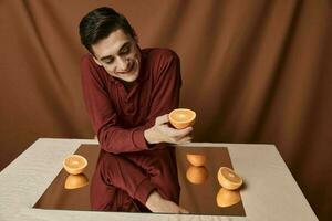 A man in a shirt at a table with a mirror reflection oranges fabric background model photo