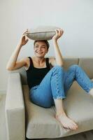 Young woman with short haircut hair having fun at home on the couch smile and happiness, vacation at home, natural posing without filters, free copy space photo