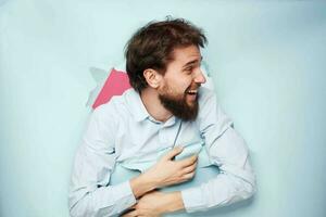 Emotional bearded man peeks out from behind the wall in office work shirt photo