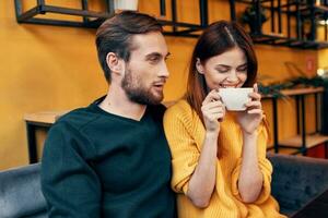 hermoso hombre en suéter y mujer con un taza de café fecha amor restaurante café foto