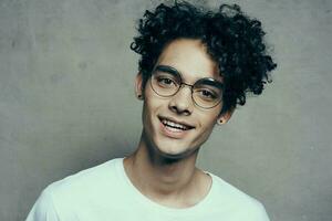 funny curly guy in a white t-shirt glasses emotions studio fashion photo