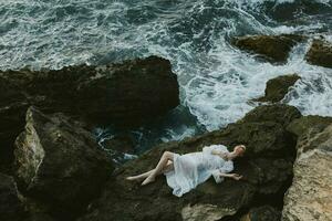 attractive woman with long hair Lies on his back on a stone cliff, cloudy weather view from above photo