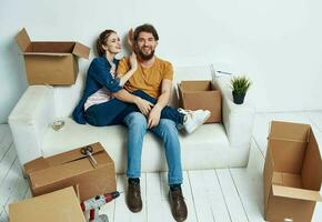 A woman-man with a flower in a pot lie on the floor In a bright room near the sofa photo