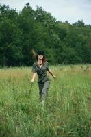 Woman on nature In a green jumpsuit, a black cap is a tall grass landscape photo