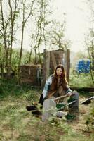 A woman pours food into a bird feeder while sitting in a chicken pen in the countryside on a summer day in the sunlight. The concept of ecological care and organic farming photo